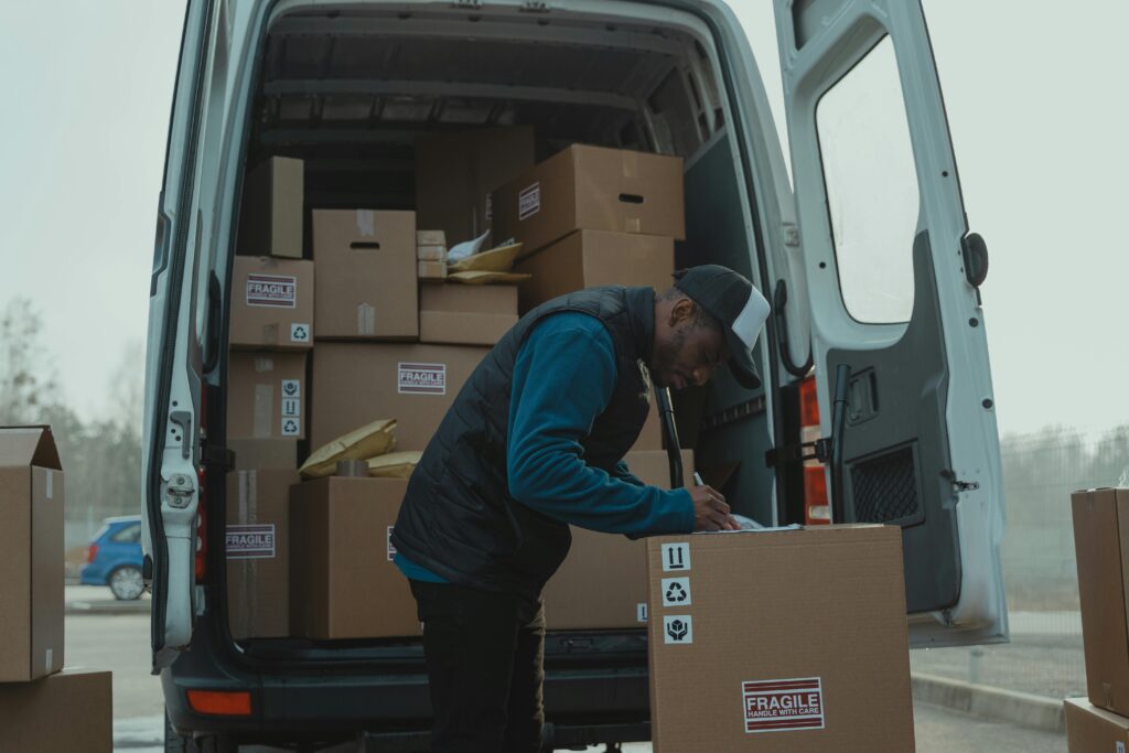 Delivery man sorting packages in van, organizing shipments for distribution.
